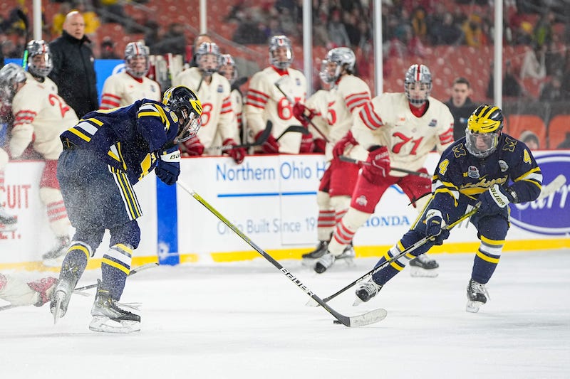 Michigan Wolverines' Gavin Brindley and Adam Fantilli reach for a puck during the Faceoff on the Lake outdoor NCAA men s hockey game against the Ohio State Buckeyes at FirstEnergy Stadium.