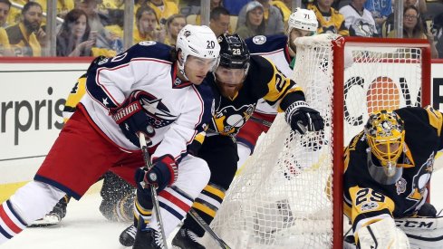 Brandon Saad works his way around the net with Ian Cole draped on his back.