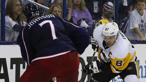 Jack Johnson of the Columbus Blue Jackets meets the Pittsburgh Penguins' Sidney Crosby behind the net.