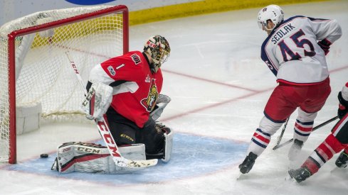 Lukas Sedlak sliding a puck past Mike Condon for a goal