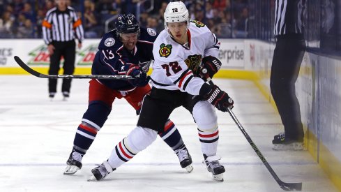 Cam Atkinson tries to push Artemi Panarin off of the puck as he gains the offensive zone.