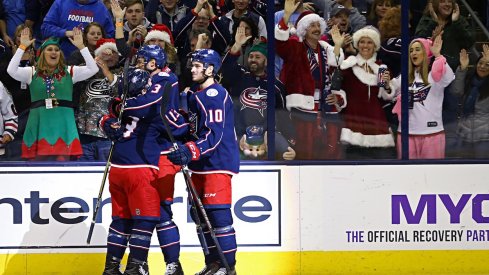 Seth Jones celebrates his goal with his teammates as holiday themed fans look on