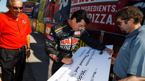 Papa John signs a big check at a racing event