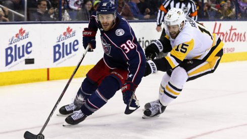 Columbus Blue Jackets forward Boone Jenner skates with the puck against Pittsburgh Penguins forward Riley Sheahan in a game at Nationwide Arena.