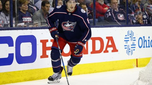Zach Werenski skates down the ice with his head up looking for a pass.