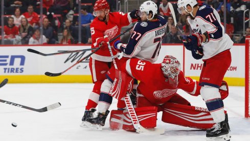 Mike Green checks Josh Anderson into goaltender Jimmy Howard