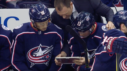 Brad Larsen talks to forwards on the bench before game play starts back up again.