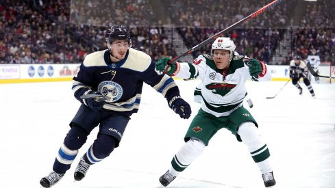 Zach Werenski and Markus Granlund chase after a puck as the Columbus Blue Jackets play the Minnesota Wild