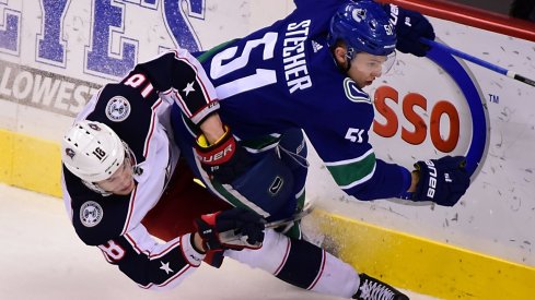 Blue Jackets' Pierre-Luc Dubois fights for the puck against Canucks defenseman Troy Stecher