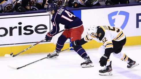 Defenseman Dean Kukan attempts to skate by Boston Bruins forward Sean Kuraly