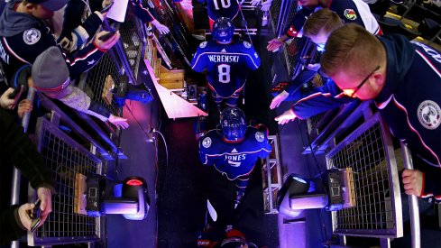 Columbus Blue Jackets defenseman Zach Werenski (8), defenseman Seth Jones (3), and center Pierre-Luc Dubois (18) high fives fans as they take the ice during warmups prior to the game against the Detroit Red Wings at Nationwide Arena.