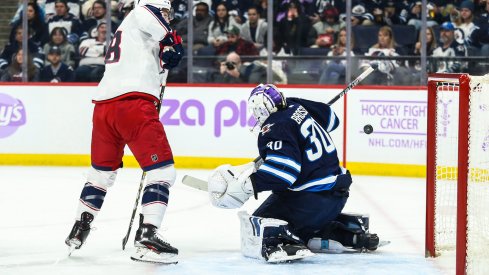 Nov 23, 2019; Winnipeg, Manitoba, CAN; Winnipeg Jets goalie Laurent Brossoit (30) makes a save with Columbus Blue Jackets forward Pierre Luc Dubois (18) looking for a rebound during the first period at Bell MTS Place. Mandatory Credit: Terrence Lee-USA TODAY Sports