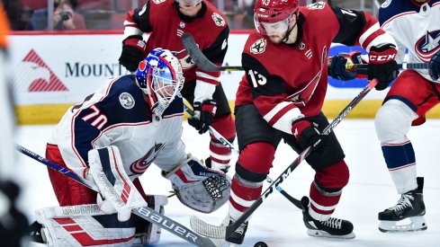 Nov 7, 2019; Glendale, AZ, USA; Arizona Coyotes center Vinnie Hinostroza (13) and Columbus Blue Jackets goaltender Joonas Korpisalo (70) battle for the puck during the second period at Gila River Arena. Mandatory Credit: Matt Kartozian-USA TODAY Sports
