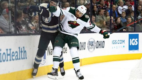 Columbus Blue Jackets defenseman Markus Nutivaara (65) is checked along the boards by Minnesota Wild right wing J.T. Brown (23) in the first period at Nationwide Arena.