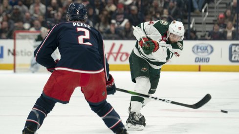 Feb 28, 2020; Columbus, Ohio, USA; Minnesota Wild center Alex Galchenyuk (27) shoots the puck past Columbus Blue Jackets defenseman Andrew Peeke (2) during the game at Nationwide Arena.