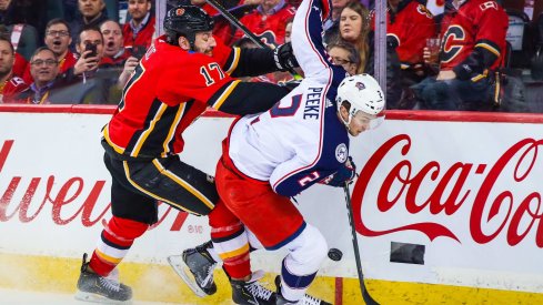 Mar 4, 2020; Calgary, Alberta, CAN; Columbus Blue Jackets defenseman Andrew Peeke (2) and Calgary Flames left wing Milan Lucic (17) battle for the puck during the first period at Scotiabank Saddledome.