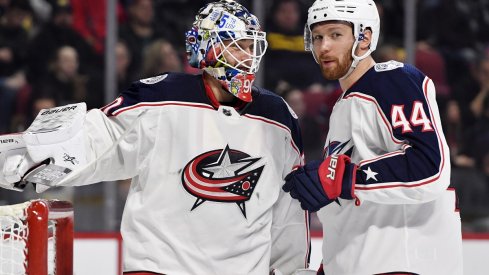 Elvis Merzlikins and Vladislav Gavrikov chat during a game