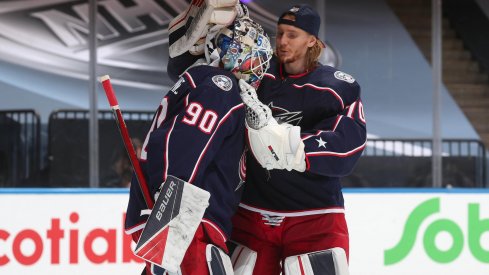 Goaltender Joonas Korpisalo #70 of the Columbus Blue Jackets congratulates fellow netminder Elvis Merzlikins #90 after an exhibition game against the Boston Bruins prior to the 2020 NHL Stanley Cup Playoffs at Scotiabank Arena on July 30, 2020 in Toronto, Ontario. The Blue Jackets defeated the Bruins 4-1.