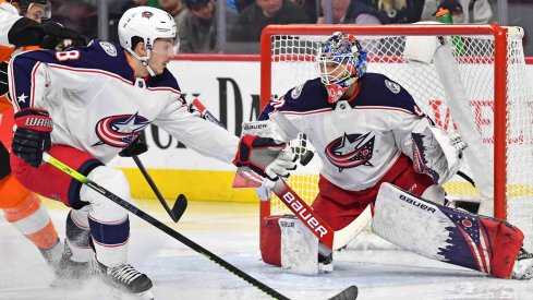 Feb 18, 2020; Philadelphia, Pennsylvania, USA; Columbus Blue Jackets defenseman Zach Werenski (8) reaches for the puck in front of goaltender Elvis Merzlikins (90) against the Philadelphia Flyers during the second period during the first period at Wells Fargo Center.