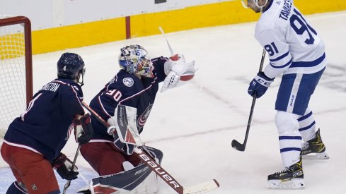 Elvis Merzlikins makes a glove save as Toronto Maple Leafs forward John Tavares