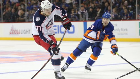 Former Columbus Blue Jacket Josh Anderson tries to get rid of the puck before he is tracked down by Islanders forward Cal Clutterbuck.