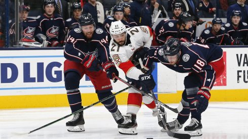 Pierre-Luc Dubois and Vladislav Gavrikov fight for possession with Vincent Trocheck