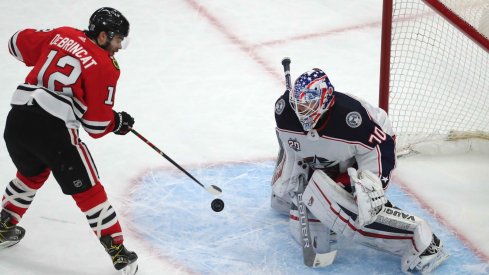 Feb 13, 2021; Chicago, Illinois, USA; Chicago Blackhawks left wing Alex DeBrincat (12) scores the game winning goal against Columbus Blue Jackets goaltender Joonas Korpisalo (70) during the overtime period at the United Center. Chicago won 3-2.