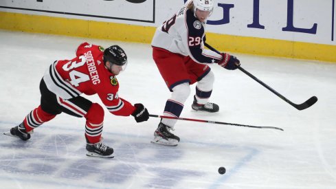 Feb 13, 2021; Chicago, Illinois, USA; Chicago Blackhawks center Carl Soderberg (34) and Columbus Blue Jackets right wing Patrik Laine (29) chase the puck during the third period at the United Center. Chicago won 3-2 in overtime.