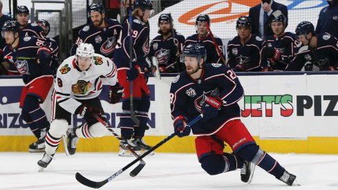Feb 25, 2021; Columbus, Ohio, USA; Columbus Blue Jackets right wing Oliver Bjorkstrand (28) grabs a loose puck against the Chicago Blackhawks during the first period at Nationwide Arena.