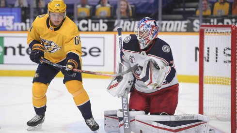 Feb 27, 2021; Nashville, Tennessee, USA; Columbus Blue Jackets goaltender Joonas Korpisalo (70) blocks a deflection by Nashville Predators center Mikael Granlund (64) during the first period at Bridgestone Arena.