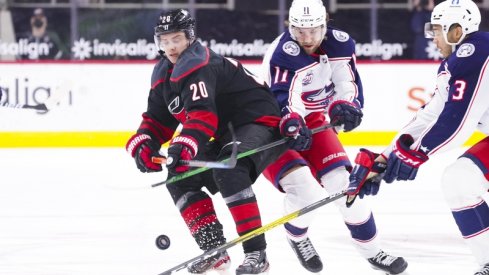 Carolina Hurricanes right wing Sebastian Aho (20) chips the puck away from Columbus Blue Jackets center Kevin Stenlund (11) during the third period at PNC Arena. 