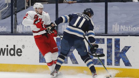 Mar 25, 2021; Columbus, Ohio, USA; Carolina Hurricanes left wing Jordan Martinook (48) and Columbus Blue Jackets center Kevin Stenlund (11) battle for the puck during the third period at Nationwide Arena.