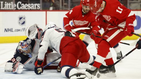 Detroit Red Wings right wing Filip Zadina (11) and Columbus Blue Jackets defenseman David Savard (58) battle for the puck in front of. goaltender Elvis Merzlikins (90) in the second period at Little Caesars Arena.