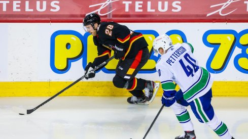 Elias Lindholm protects the puck from Elias Pettersson