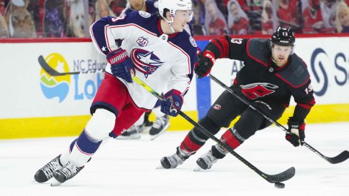 Mar 18, 2021; Raleigh, North Carolina, USA; Columbus Blue Jackets defenseman Zach Werenski (8) skates with the puck past Carolina Hurricanes left wing Warren Foegele (13) at PNC Arena.