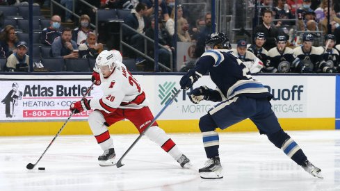 Sebastian Aho of the Carolina Hurricanes carries the puck against Adam Boqvist of the Columbus Blue Jackets.