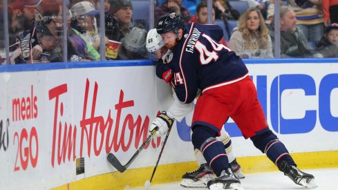 Columbus Blue Jackets defenseman Vladislav Gavrikov (44) pins Buffalo Sabres left wing Victor Olofsson (68) on the boards as he goes for the puck during the second period at KeyBank Center.