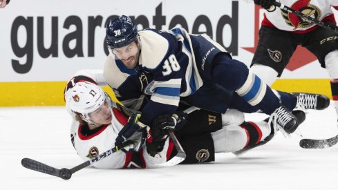 Jan 23, 2022; Columbus, Ohio, USA; Columbus Blue Jackets center Boone Jenner (38) tries to maintain control of the puck as he falls to the ice with Ottawa Senators center Adam Gaudette (17) in the second period at Nationwide Arena.