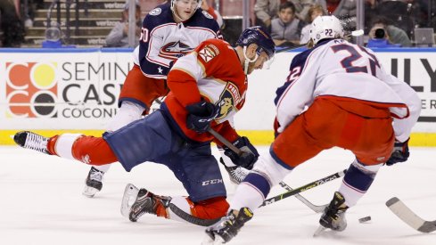 Eric Robinson and Jake Bean try to take the puck from Jonathan Huberdeau 