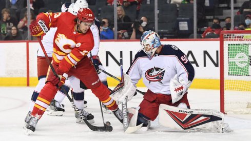 Calgary Flames forward Sean Monahan playing the puck against Columbus Blue Jackets goalie Elvis Merzlikins during the first period in Calgary.