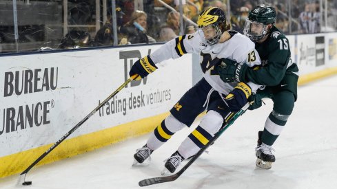 Michigan forward Kent Johnson (13) is defended by Michigan State defenseman Christian Krygier (15) during the first period of the first game in their Big Ten quarterfinal matchup at Yost Ice Arena in Ann Arbor on Friday, March 4, 2022.