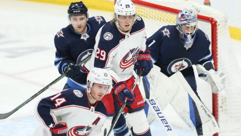 Winnipeg Jets defenseman Neal Pionk jostles for position with Columbus Blue Jackets forward Patrik Laine in front of Winnipeg Jets goalie Eric Comrie during the third period at Canada Life Centre