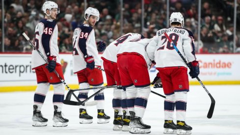 Zach Werenski is helped off by teammates in the first period of Columbus' 3-2 overtime loss to the Minnesota Wild.