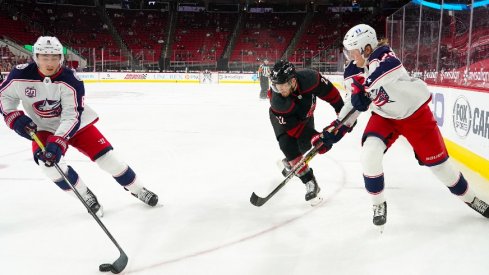 Columbus Blue Jackets defenseman Zach Werenski with right wing Patrik Laine skates with the puck past Carolina Hurricanes defenseman Brett Pesce at PNC Arena.