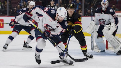 Boone Jenner battles for a buck in front of the Blue Jackets net against the Vancouver Canucks.