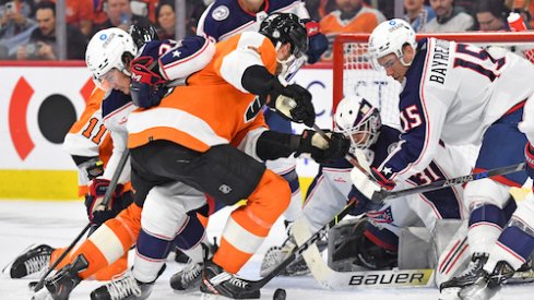 Philadelphia Flyers left wing Noah Cates (49) battles for the puck with Columbus Blue Jackets defenseman Andrew Peeke (2) and defenseman Gavin Bayreuther (15) during the second period at Wells Fargo Center.