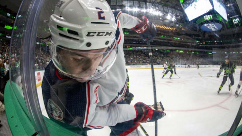 Columbus Blue Jackets' Andrew Peeke is checked into the glass as he battles for control of the puck during the second period against the Dallas Stars at the American Airlines Center.