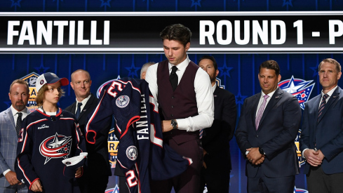 Adam Fantilli puts on a Blue Jackets jersey after being selected with the third pick in round one of the 2023 NHL Draft
