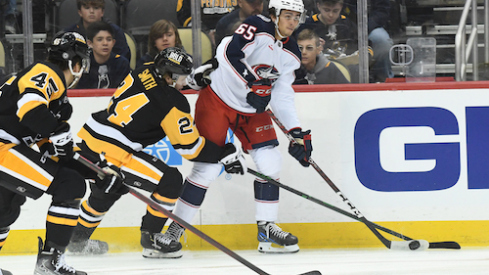 Columbus Blue Jackets center Luca Del Bel Belluz (65) moves the puck away from Pittsburgh Penguins defenseman Ty Smith (24) and forward Jonathan Gruden (45) during the first period at PPG Paints Arena.