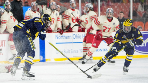 Michigan Wolverines forwards Gavin Brindley (4) and Adam Fantilli (19) reach for a puck during the Faceoff on the Lake outdoor NCAA men's hockey game against the Ohio State Buckeyes at FirstEnergy Stadium.